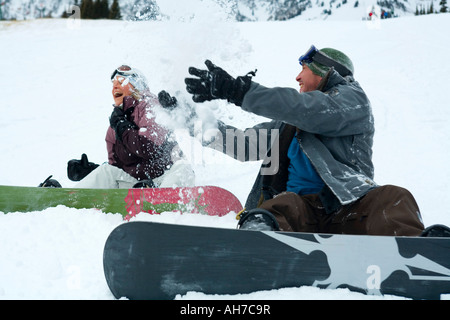 Mitte erwachsenes paar sitzen und werfen Schnee Stockfoto