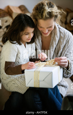 Mitte Erwachsene Frau und ihrer Tochter ein Weihnachtsgeschenk zu öffnen Stockfoto