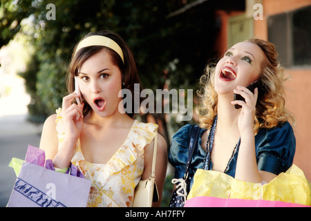 Zwei junge Frau auf dem Handy sprechen und halten Einkaufstaschen Stockfoto