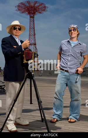 Junge Mann stand neben einem älteren Mann mit einer Kamera, Parachute Drop, Coney Island, New York City, New York, USA Stockfoto