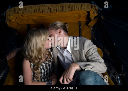Junges Paar küssen einander in einem bespannten Wagen Stockfoto