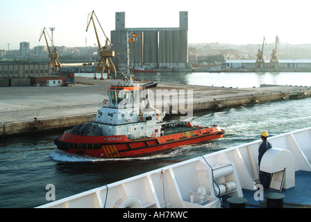 Hafenanlagen in Tarragona mit Schleppboot Romulo auf dem Weg vorbei an einem Kreuzfahrtschiff, das ein Mitglied der Hafenbesatzung mit Blick auf spanien betritt Stockfoto