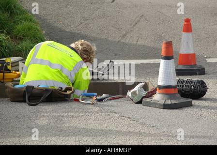 Britischer Telekommunikationsingenieur, der in einem Straßenschachtloch sitzt und an unterirdischen Telefonkabeln arbeitet Cornwall England Vereinigtes Königreich Großbritannien Stockfoto