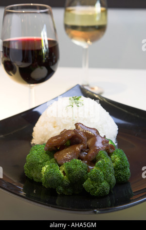 Das klassische Gericht aus Rindfleisch Brokkoli und Reis serviert mit Rotwein Stockfoto