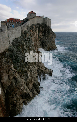 Ummauerten Stadt Dubrovnik überragt Wellen gegen den Fuß der Klippen an der mediterranen Küste von Kroatien Stockfoto