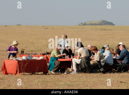 Touristen genießen ein Open-Air-Frühstück nach einem Ballon fahren in der Masai Mara National Reserve Kenia in Ostafrika Stockfoto