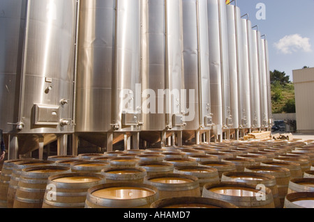 Wein Gärung Edelstahltanks mit Reihen von Eiche Weinfässer im Vordergrund auf dem Regaliali Weingut in Sizilien Stockfoto