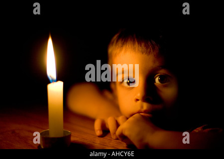 Kopf und Schultern Porträt eines kleinen Jungen im Kerzenlicht Stockfoto