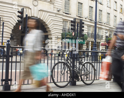 ein Fahrrad angekettet an Eisengitter in Regent Street London verschwommene Shopper Durchgang von Einkaufstaschen tragen Stockfoto