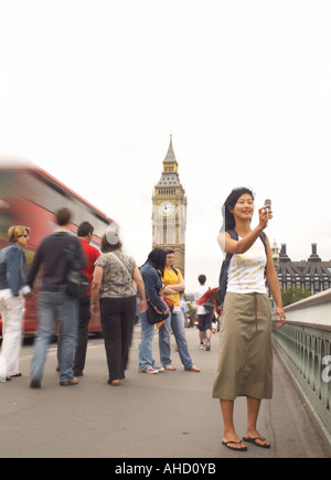 orientalische Frau, die ein digitales Mobiltelefon Selbstbildnis auf Westminster Bridge mit Big Ben und London Bus Stockfoto