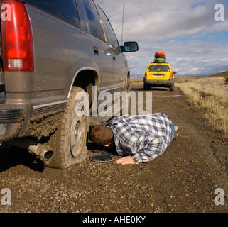 Man legt schlammigen unterwegs eine Reifenpanne auf seinem SUV ändern Stockfoto