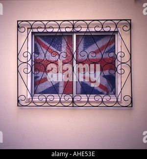 Ein Union Jack-Flagge hinter einem Küchenfenster auf einer Wohnsiedlung in Gibraltar. Stockfoto