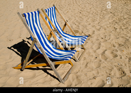 Zwei blau-weiß gestreiften Liegestühlen am Strand von Swanage, Dorset, England Stockfoto