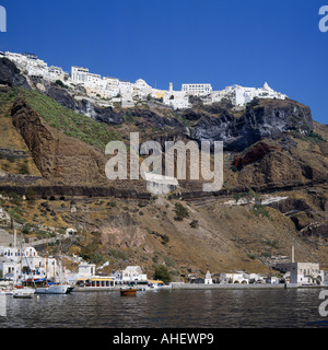 Blick über Wasser, steile Klippen mit weißen Gebäuden am oberen und kleinen Hafen unterhalb Fira auf Santorin die griechischen Inseln Stockfoto