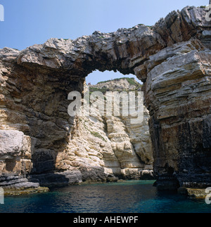 Blick durch den Bogen des Tripito mit Menschen auf der Klippe auf West Coast Paxos Insel der Ionischen Insel Gruppe griechische Inseln Griechenland Stockfoto