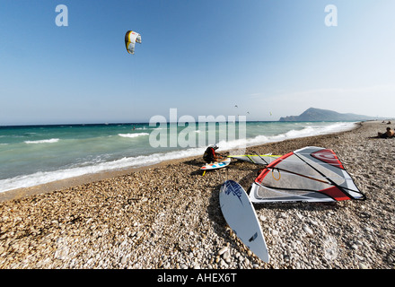 Windsurfer am Strand neben seinem Brett sitzt und Uhren Kitesurfer im Mittelmeer Stockfoto