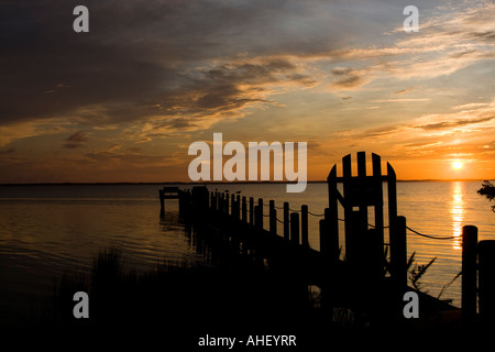 Leuchtend bunte Sonnenuntergang an der Bay, North Carolina, gated Dock und Wolken. Gliederung von Möwen auf Beiträge. Stockfoto