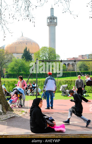 Die Londoner Moschee Kuppel & Minarett, Regents Park Kinderspielplatz mit Schaukeln & Sandkasten & Dame im arabischen Kleid im Vordergrund Stockfoto