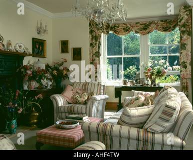 Gestreiften Sofa und Sessel im Kleinstaat Wohnzimmer mit Blick auf Garten durch das Fenster Stockfoto