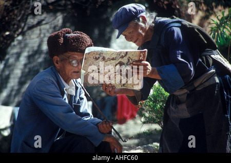 Eine alte Dame aus der Naxi-Minderheit zeigt einem älteren Mann eine Buch, Lijiang, Yunnan Provinz, China. 1991. Stockfoto