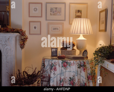 Beleuchtete Lampe am runden Tisch mit floralen Tuch in der Ecke des Wohnzimmers kleines Land Stockfoto