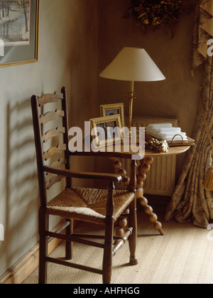 Rush sitzen Ladderback Stuhl und Pinien-Tisch mit Spindel Beine in Ecke des Landes Speisesaal Stockfoto