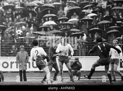 Fußball, Bundesliga, 1971/1972, Niederrhein-Stadion in Oberhausen, Rot-Weiss Oberhausen vs. FC Schalke 04 2:3, Regenwetter, Spiel bei starkem Regen, Zuschauer und Fußball-mit Sonnenschirmen, Szene des Spiels, v.l.n.r.: Reiner Hollmann (RWO), Herbert Fans Stockfoto