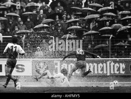 Fußball, Bundesliga, 1971/1972, Niederrhein-Stadion in Oberhausen, Rot-Weiss Oberhausen vs. FC Schalke 04 2:3, Regenwetter, Spiel bei starkem Regen, Zuschauer und Fußball-mit Sonnenschirmen, Szene des Spiels, Uwe Kliemann (RWO, 5) in einer Wasserpfütze Fans Stockfoto