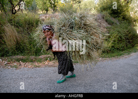 Türkische Frau mit riesigen Laden von Gräsern im türkischen Dorf Stockfoto