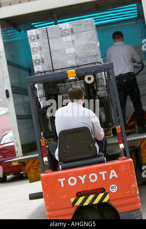 Arbeiter entladen Schweif heben LKW mit Gabelstapler mit Palette verpackt Haufen von Computer-System-Boxen Stockfoto