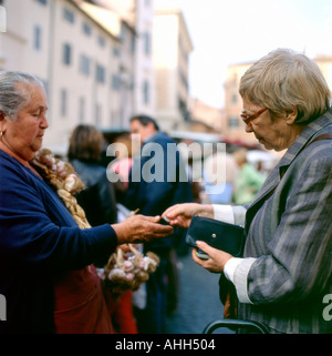 Eine Frau zahlt einen Markt-Händler in Campo dei Fiori für Knoblauch in der Straße Markt Rom KATHY DEWITT Stockfoto