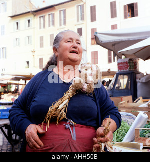 Eine ältere Frau Markthändlerin, die Zöpfe mit Knoblauchzwiebeln verkauft Am Seil in der Obst- und Gemüsstraße Campo de Fiori Lebensmittelmarkt Rom Italien KATHY DEWITT Stockfoto