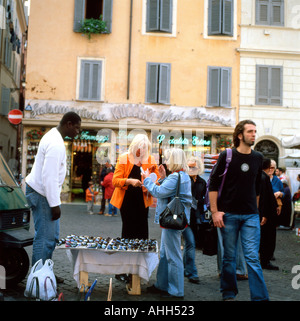 Touristen Menschen Frauen Campo dei Fiori kaufen Sonnenbrille von an Afrikanische Straßenhändler stehen am Campo de Fiori in Rom Italien Europa EU KATHY DEWITT Stockfoto