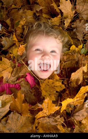 Kleines Mädchen 2 Jahre alt. im Stapel Blätter lächelnd. Stockfoto