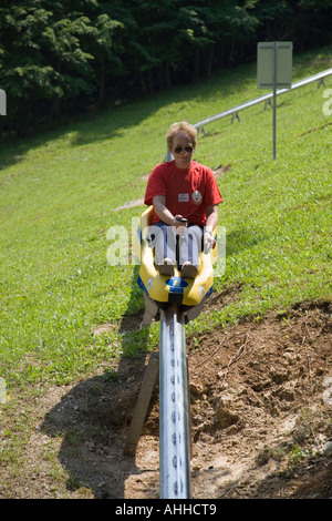 Dame saß Reiten auf gelben Schlitten herab Sommer Rodelpartie auf Metallschiene unteren Rand Speisekarte ski-Hang in Bled Stockfoto