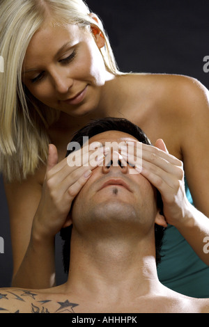 junge Frau, die Augen eines Mannes zu halten geschlossen Stockfoto