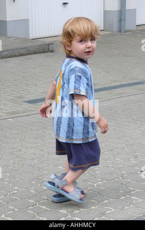 kleiner Junge in Overzized Schuhen Stockfoto