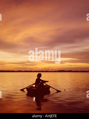 Frau Angeln vom Ruderboot bei Sonnenuntergang Stockfoto