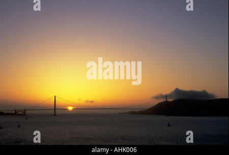 Blick über die Bucht in der Abenddämmerung auf die Golden Gate Bridge, die gegen untergehende Sonne und orangefarbenen Himmel silhouettiert ist. San Francisco, Kalifornien, USA. Stockfoto