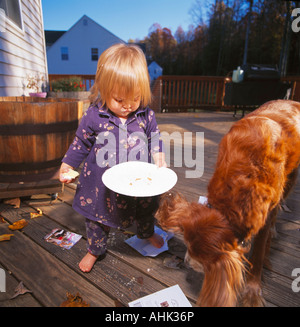 Kind/kleine Mädchen und Hund bei einem Picknick mit Essen. Stockfoto