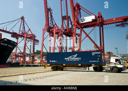 Kran-beladen LKW fahren mit NYK Logistics Frachtcontainer, Hong Kong Hafen Docks Stockfoto