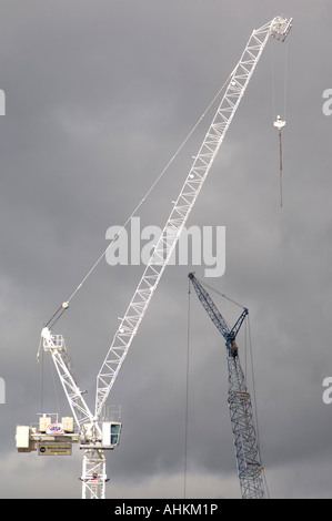 zwei Turmdrehkrane auf der Baustelle gegen Grau über Besetzung Wolken Stockfoto