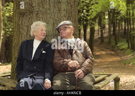 Ehepaar im Ruhestand sitzen unter einem großen Baum genießen einen Witz Stockfoto