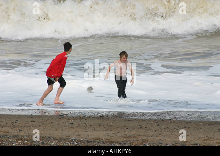 zwei Jungen spielen in Wellen am Meer. Stockfoto