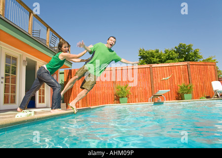 Frau, die den Mann in den Swimmingpool schiebt Stockfoto