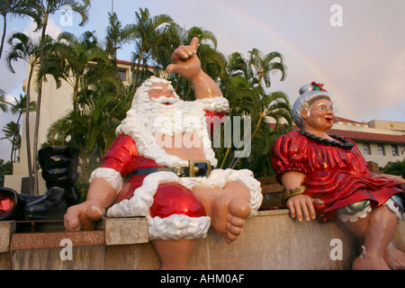 Hawaiian Santa Claus und Frau Claus auf einem Brunnen in Honolulu Hawaii Regenbogen im Hintergrund Stockfoto