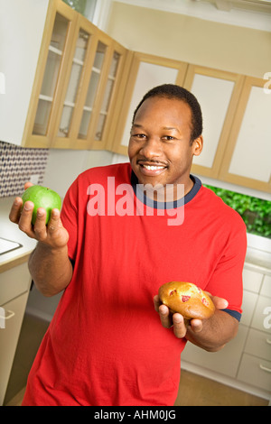 Afrikanischen Mann, hält Apple und muffin Stockfoto