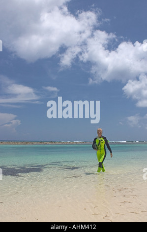 Frau in einen Neoprenanzug mit Schnorchelausrüstung zu Fuß in das Wasser an einem Strand in Kaimaninseln Cayman Brac Stockfoto