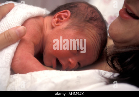 kleine Frühgeborene auf Mutters Brust im Bett liegend Stockfoto