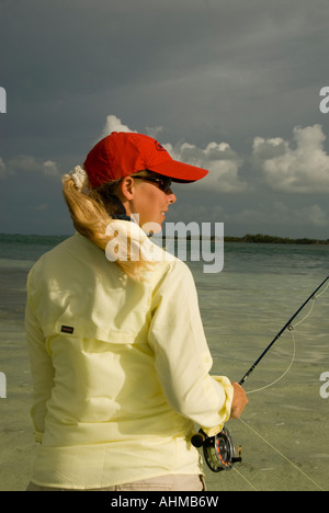 Florida Keys Frau Fischer casting für Bonefish beim Fliegenfischen unter dunklem Himmel auf den Flats auf das Karibische Meer Stockfoto